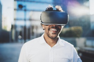 Concept of technology,gaming,entertainment and young people.Smiling american african man enjoying virtual reality glasses or 3d spectacles.Blurred background.Horizontal.